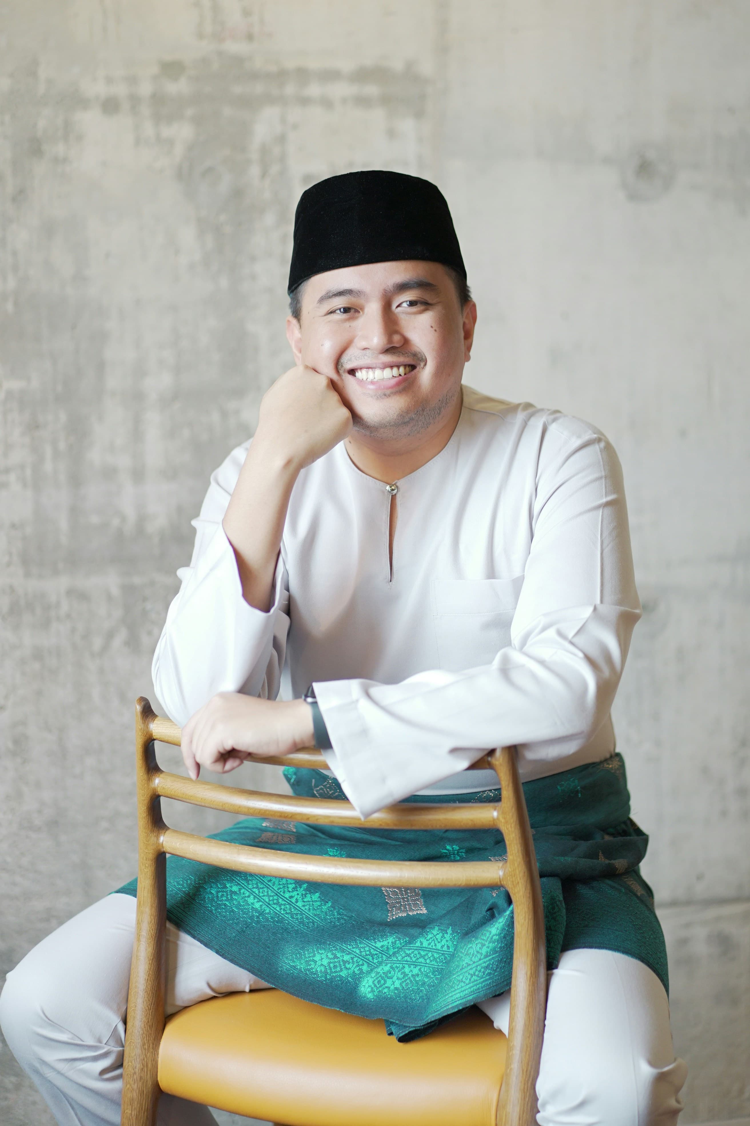 Smiling man in traditional attire seated on a chair
