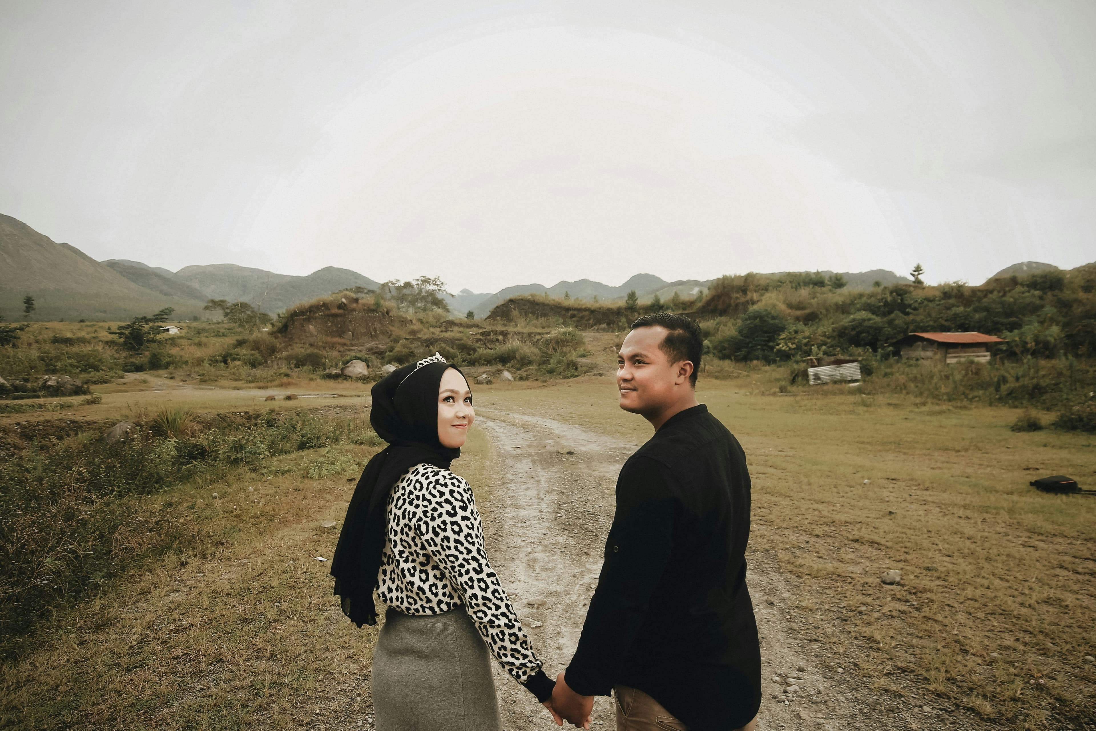A couple holding hands while walking along a mountain path